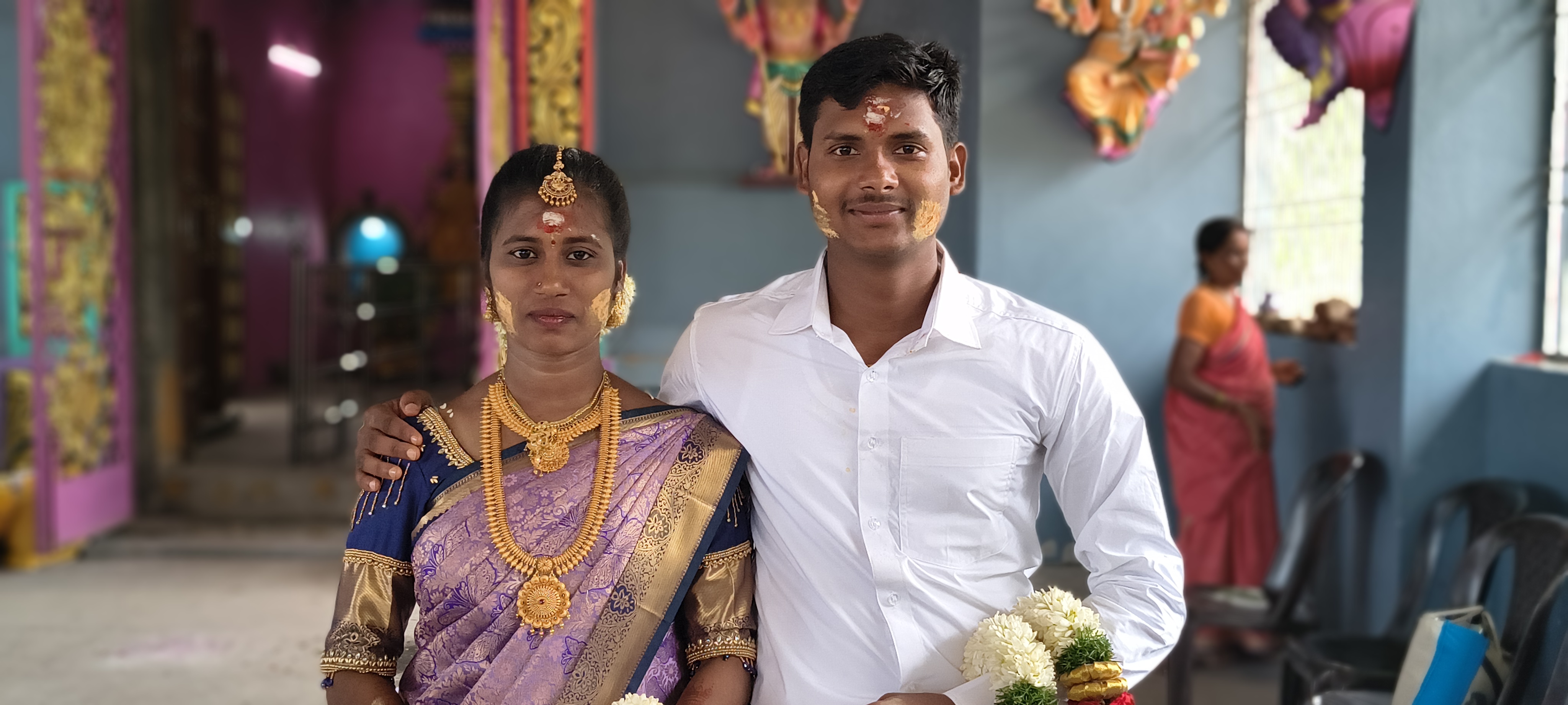 Pushpa and Hariharan at the temple, holding garlands